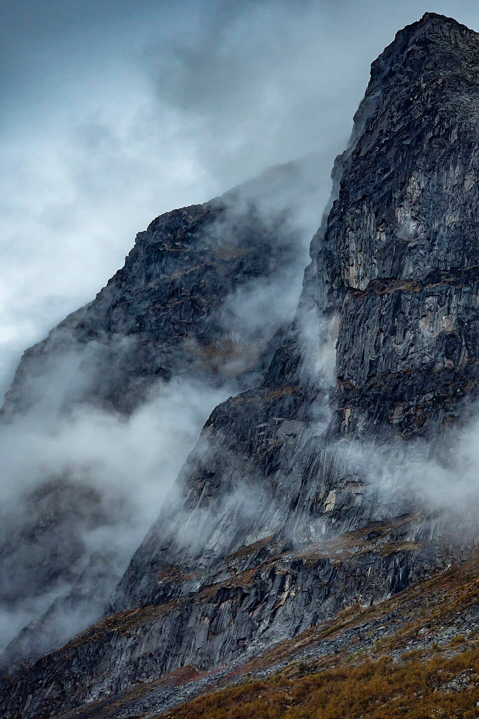 A dramatic rock face in Stora Sjöfallet/Stuor Muorkke National Park, partly shrouded in cloud and mist.